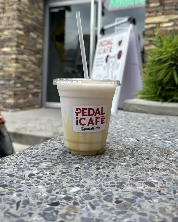 Bebida fría de PEDALiCAFÉ sobre un muro en la entrada del local